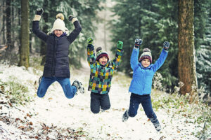 Kids enjoying the first snow in winter forest