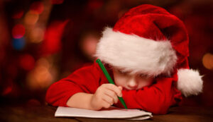 Christmas child writing letter to Santa letter over abstract bac